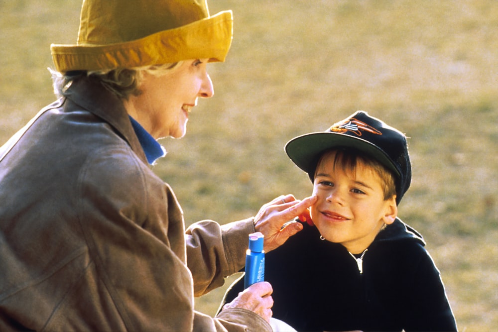 boy in black hat holding blue plastic bottle