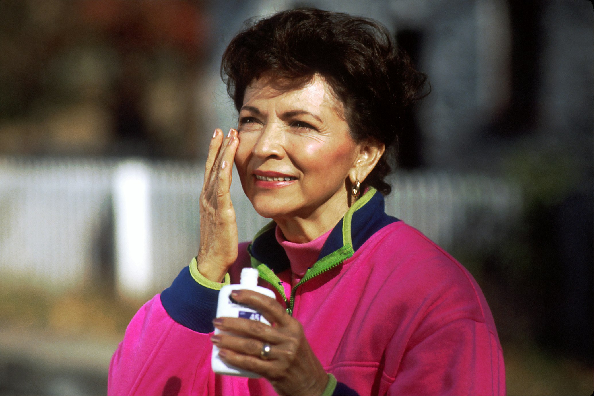 A person applying sunscreen anti-aging cream on their face.