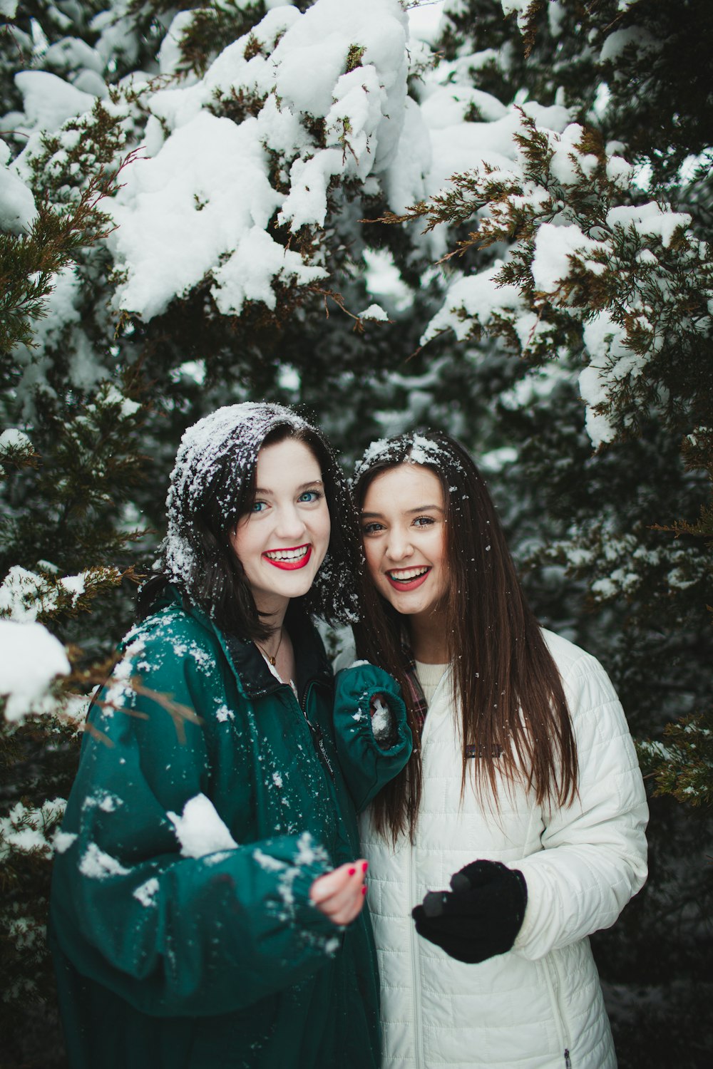 woman in white jacket smiling beside woman in blue and white floral shirt