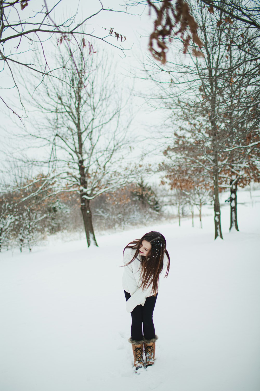 Mujer en camisa de manga larga en blanco y negro de pie en el suelo cubierto de nieve durante el día
