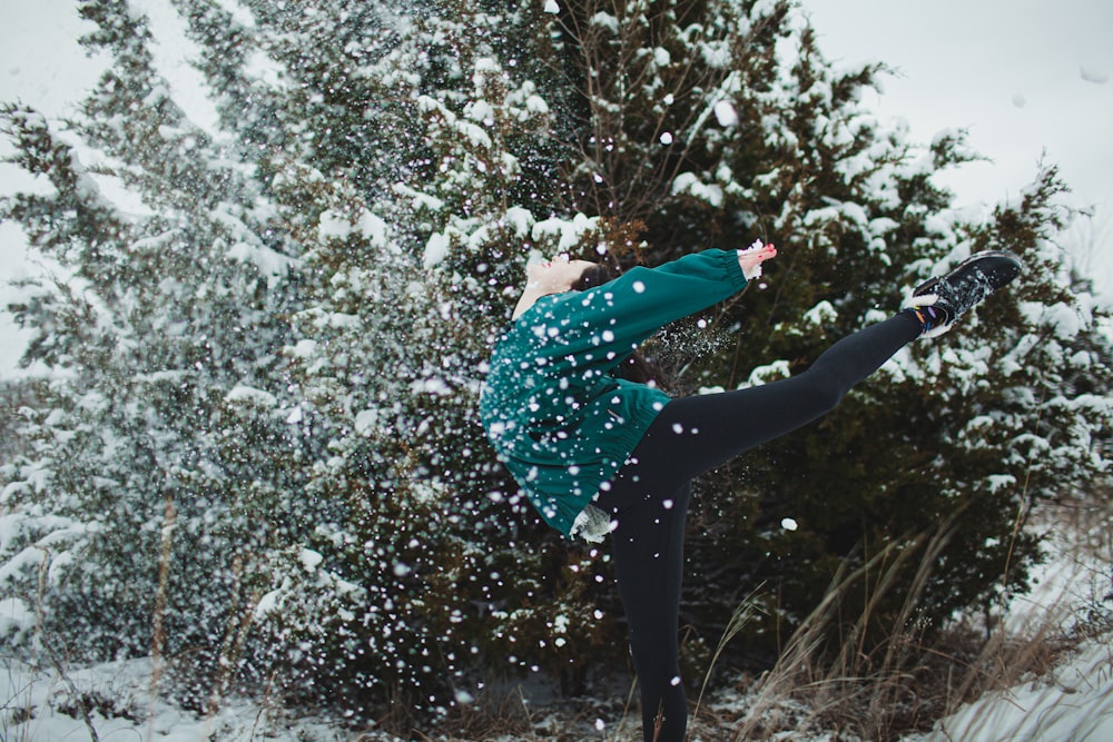 woman in green and black polka dot shirt and black pants standing on snow covered ground