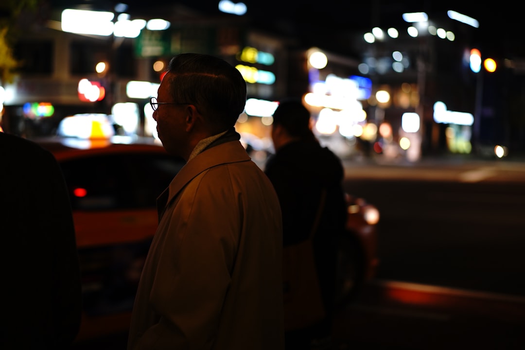 man in white coat standing near road during night time