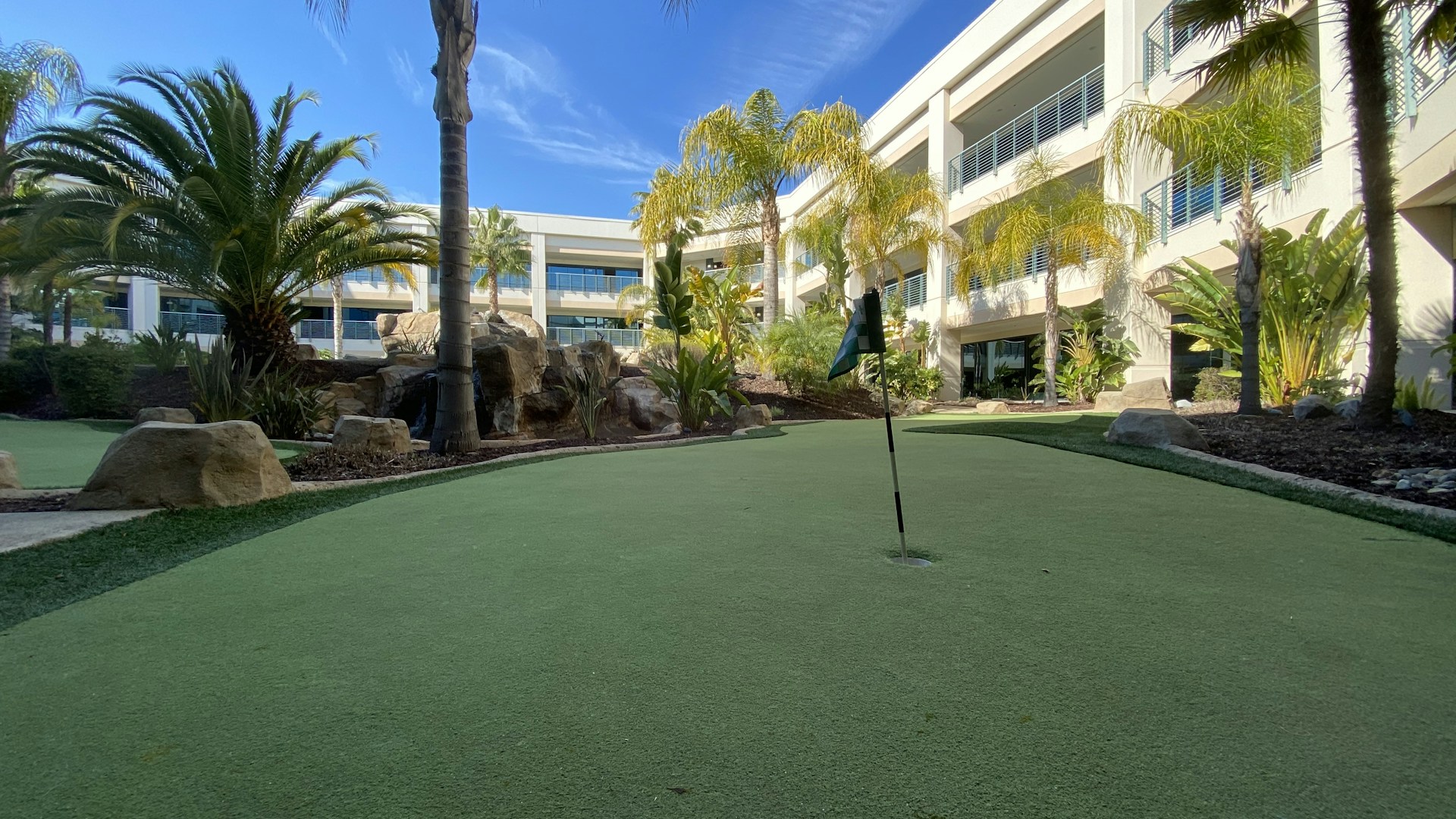 A modern condominium overlooking a golf course with spacious balconies and lush greenery.