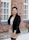 woman in black blazer and beige skirt standing near brown brick wall during daytime
