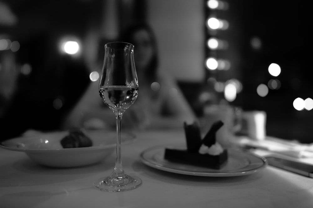 grayscale photo of wine glass on table