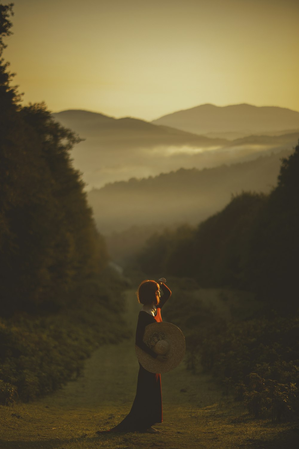 Person mit brauner Strickmütze sitzt bei Sonnenuntergang auf Felsen