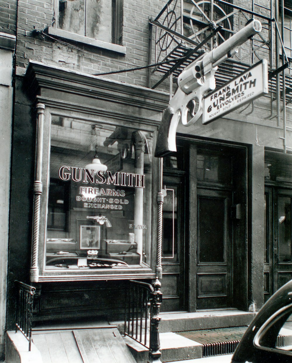 grayscale photo of Gunsmith shop window