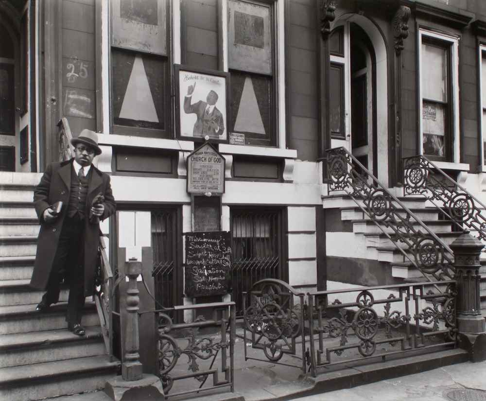 man in black coat standing on staircase near the Church of God