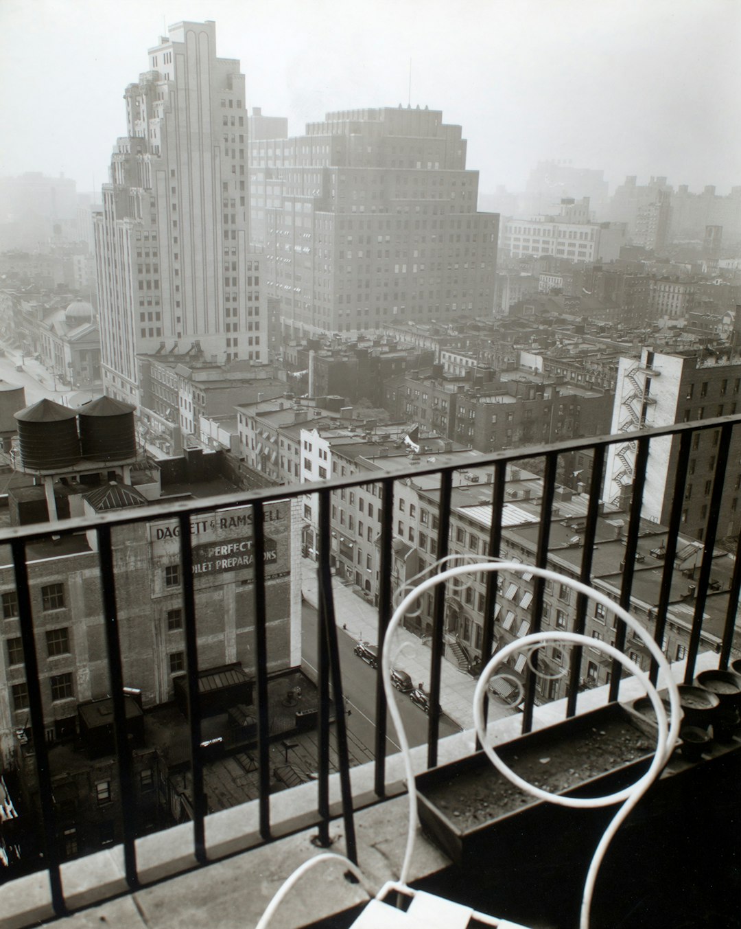 small balcony with white chair near city buildings during daytime