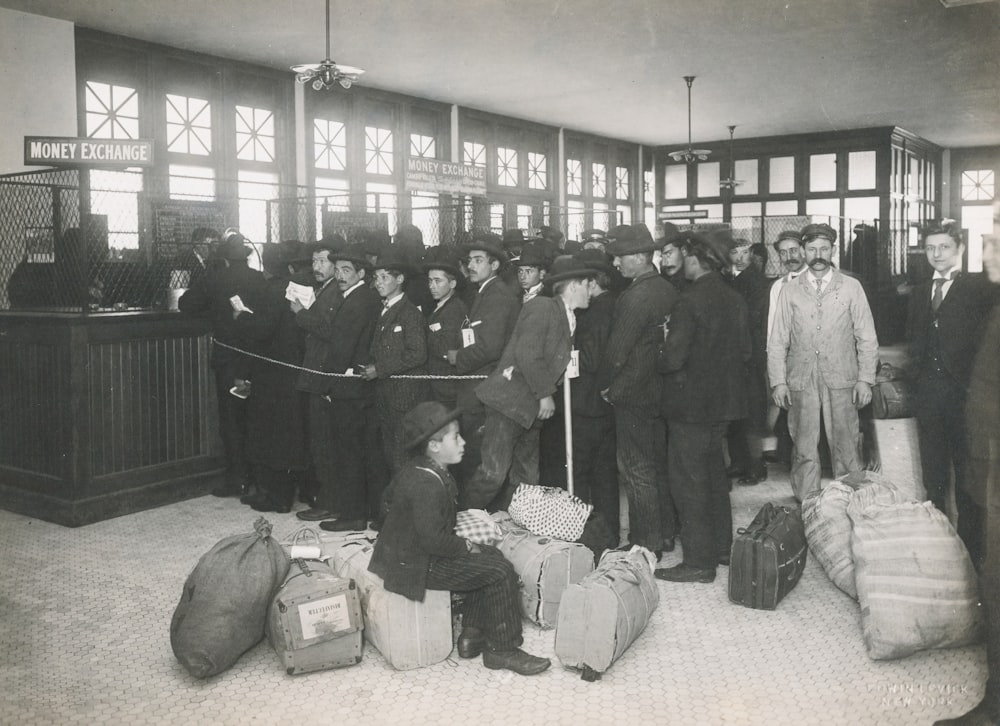 grayscale photo of a group of immigrants with bags inside
