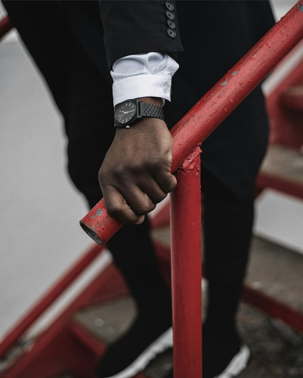 person wearing silver link bracelet watch holding red metal bar