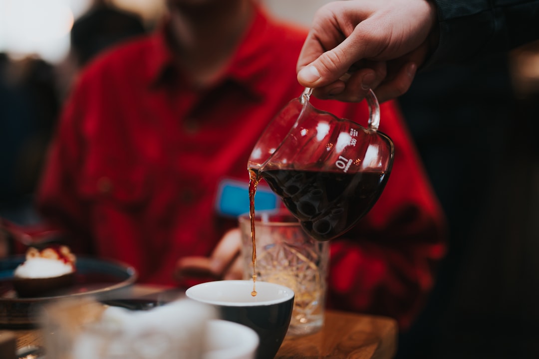 person pouring red wine on clear wine glass