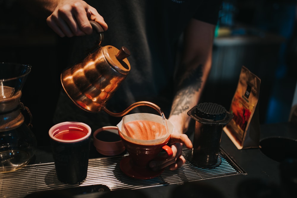 person pouring coffee on brown ceramic mug