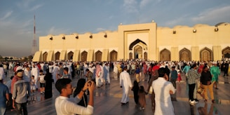 A community gathering outside a mosque, showcasing people sharing news and information.