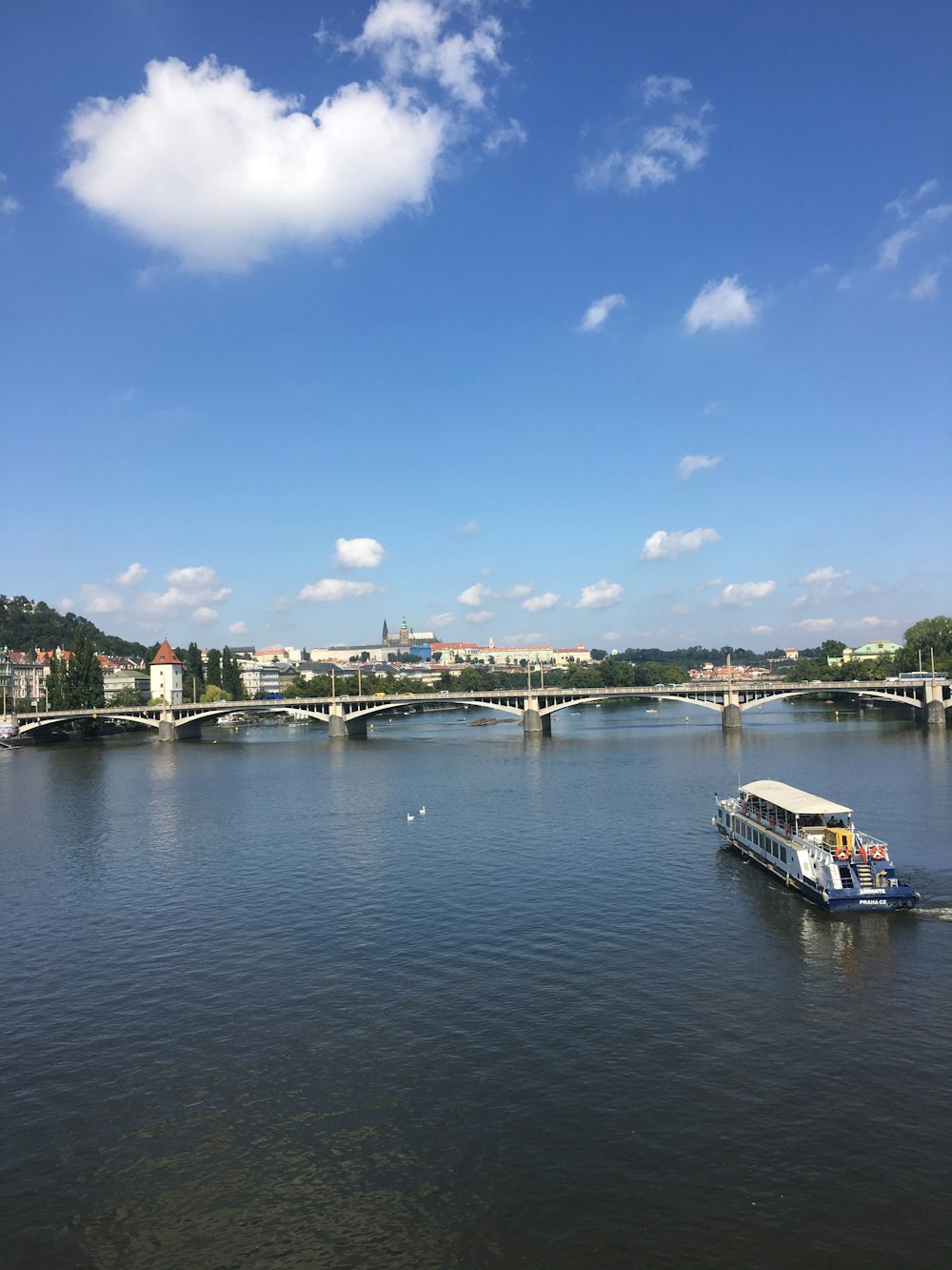 white boat on water near city buildings under blue sky during daytime