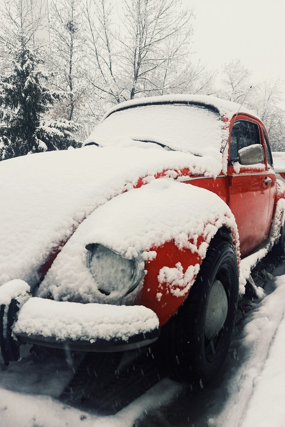 an old red truck is covered in snow