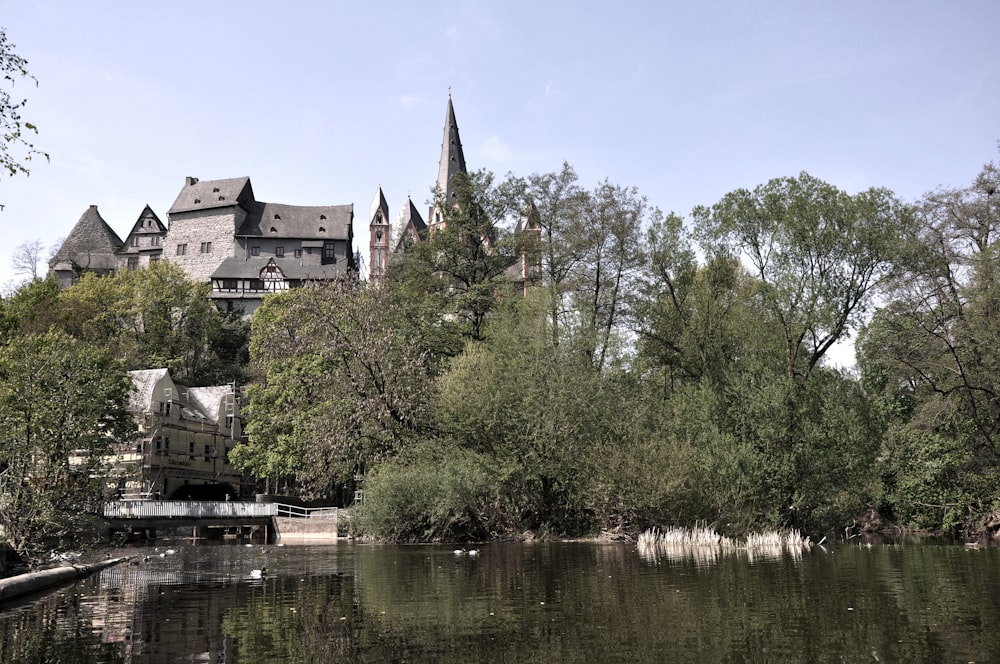 brown and gray concrete building near green trees and body of water during daytime