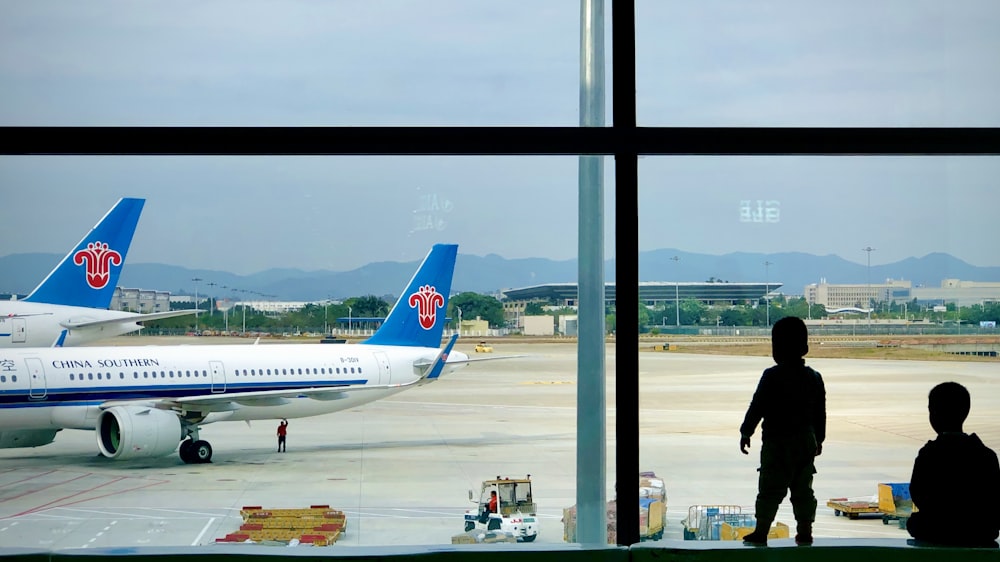 white and blue airplane in airport during daytime