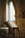 An ornate wooden lectern holds an open, aged book inside a dimly-lit, classical architectural setting with decorative arches and columns.