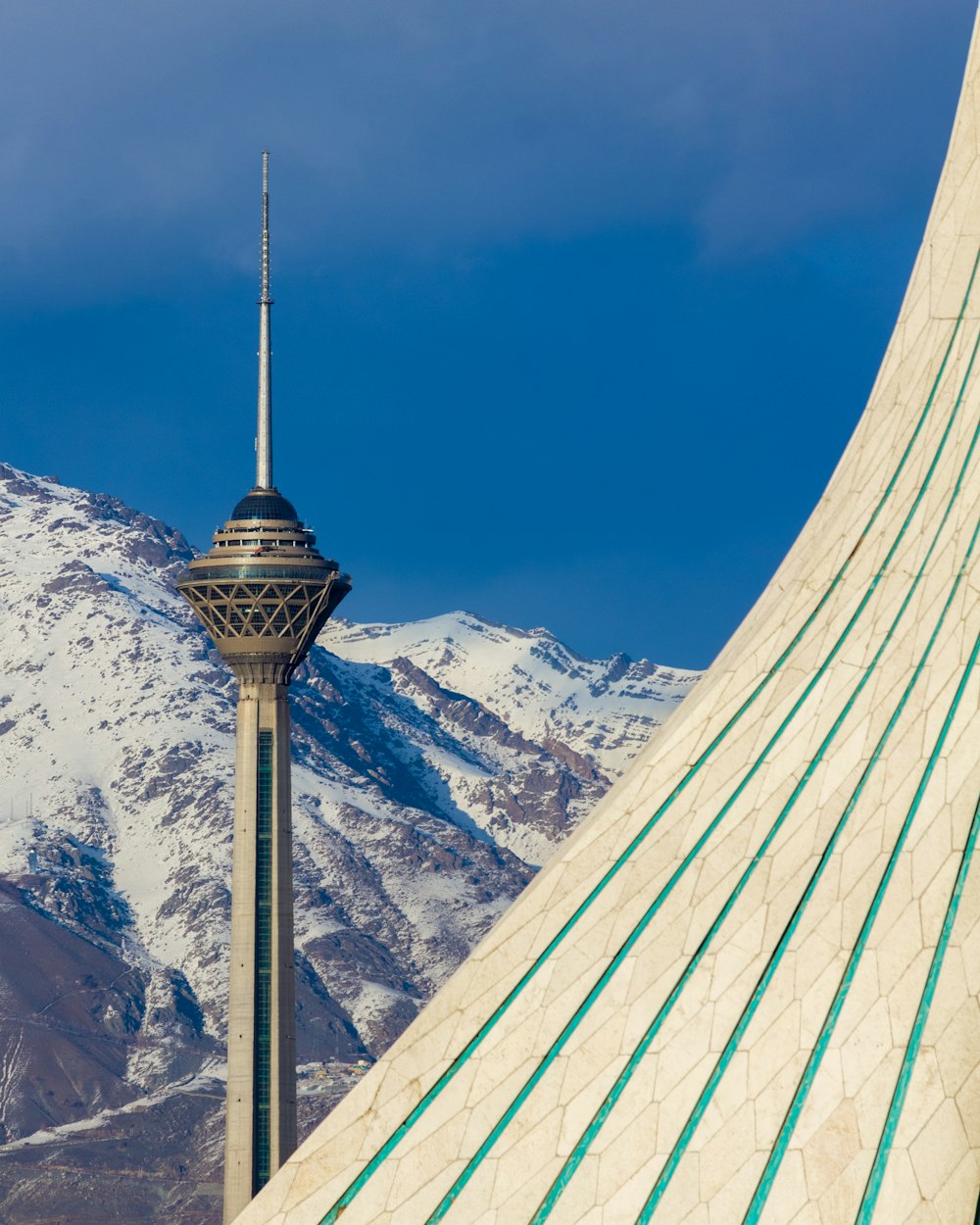 white and black tower near snow covered mountain during daytime