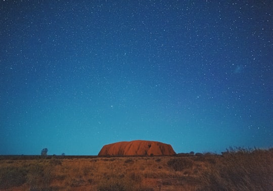 brown mountain under blue sky during night time in Ayers Rock – Uluru Australia