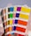 Hands inspecting printed materials with vivid colors on a desk.
