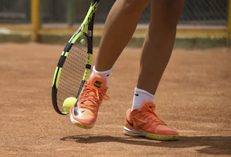 person in red nike shoes holding tennis racket