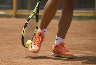 person in red nike shoes holding tennis racket