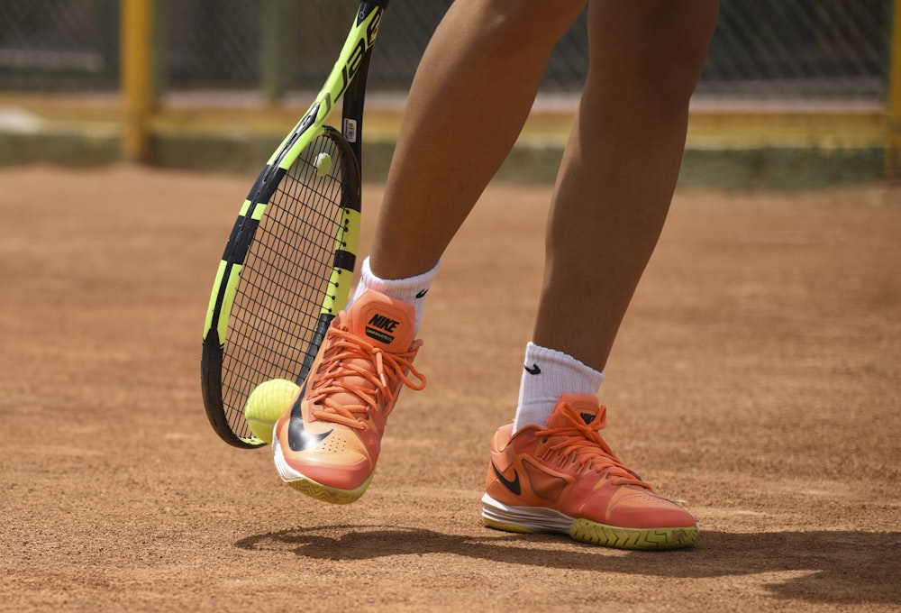 Foto Pessoa em sapatos nike vermelhos segurando raquete de tênis – Imagem  de Bem-estar grátis no Unsplash