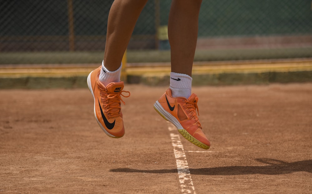 person in red nike sneakers jumping on field