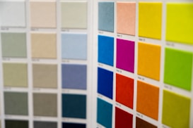 Rows of colored squares are displayed in a grid format, likely representing a selection of paint or fabric swatches. The left section consists of muted colors such as greens, beiges, and grays. The right section features more vibrant colors, including pink, purple, orange, and bright green.
