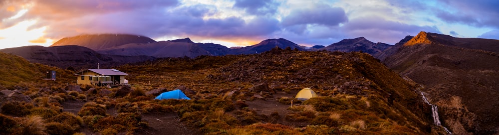 white tent on brown field near mountain under white clouds and blue sky during daytime