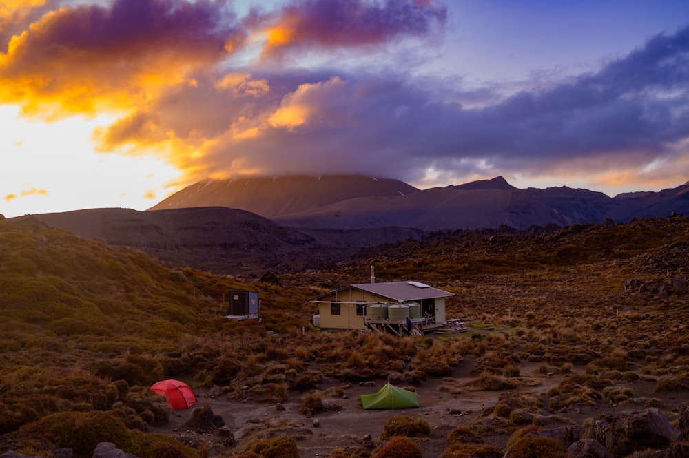 white and brown house near mountain under cloudy sky during daytime