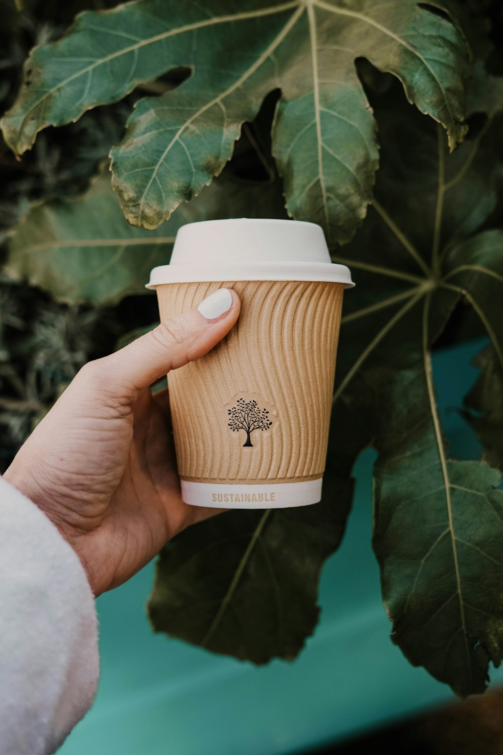 Persona che tiene la tazza di caffè bianca e marrone