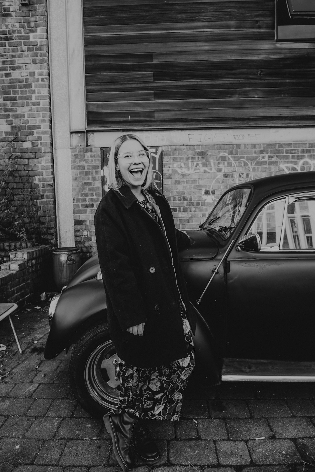 woman in black coat standing beside black car