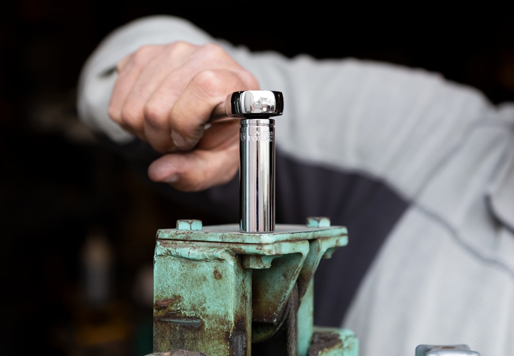 person holding green metal tool