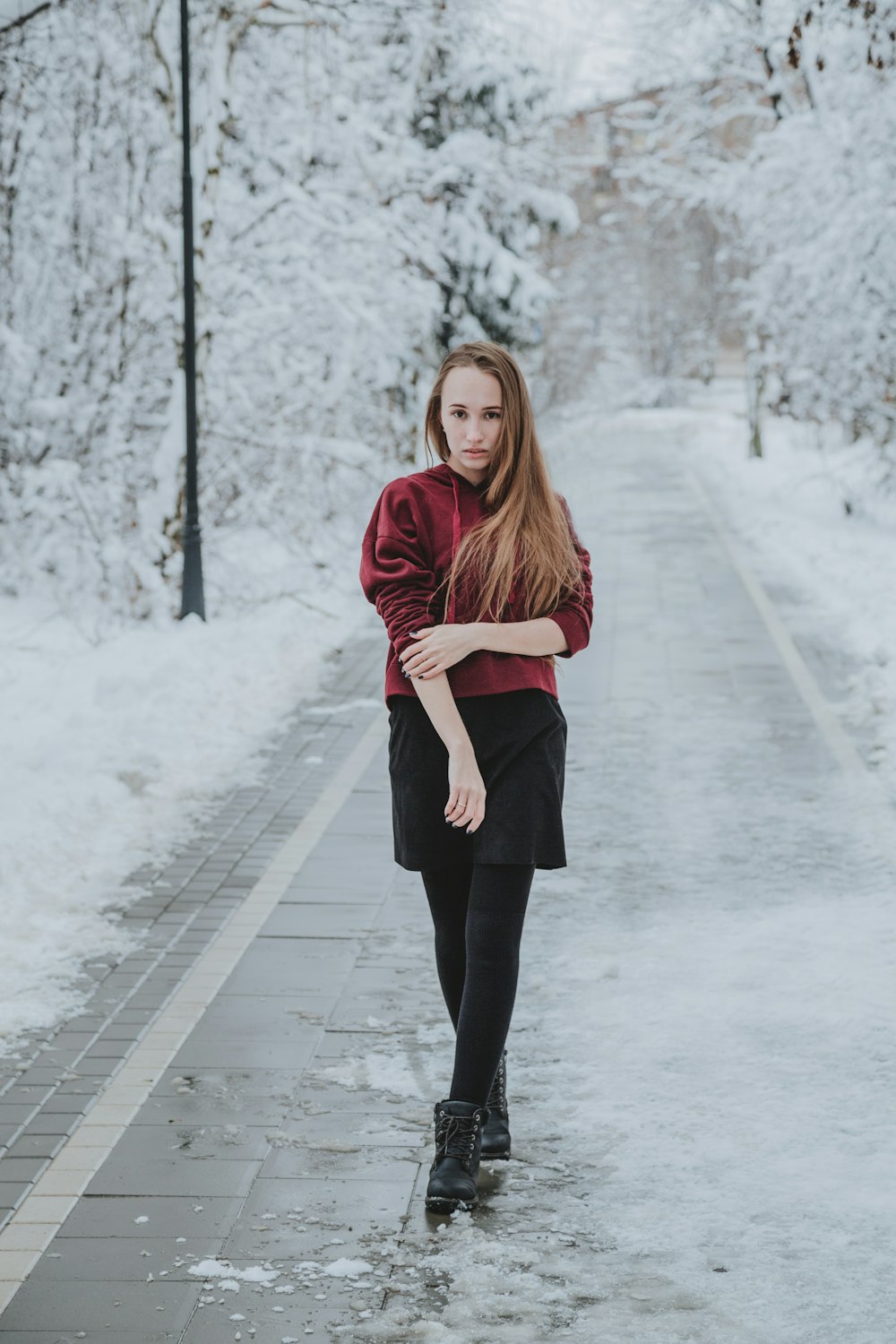 woman in red sweater and black pants standing on snow covered pathway
