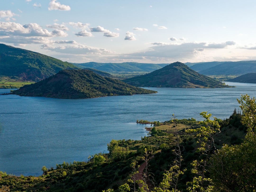 green mountains near body of water during daytime, Twin Island<p></figure>Hike around Lac du Salagou, France