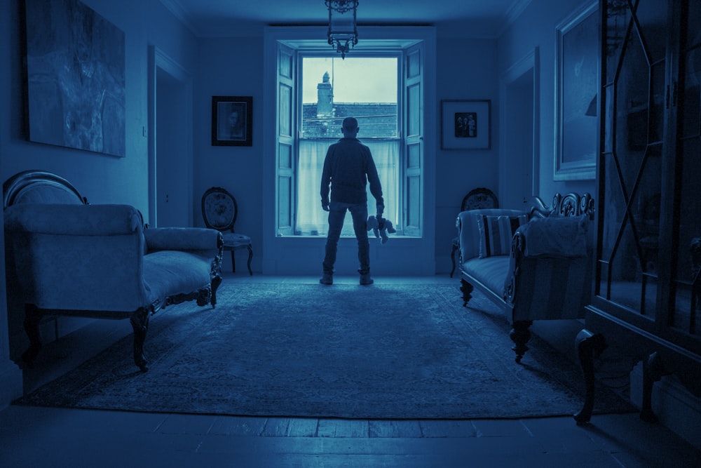 man in black t-shirt standing near white wooden door