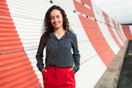 woman in black and white polka dot long sleeve shirt and red skirt standing on sidewalk