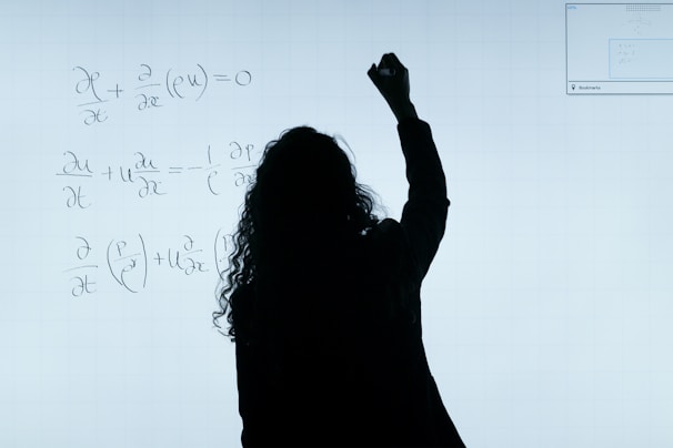 A focused researcher working with scientific equations on a whiteboard.
