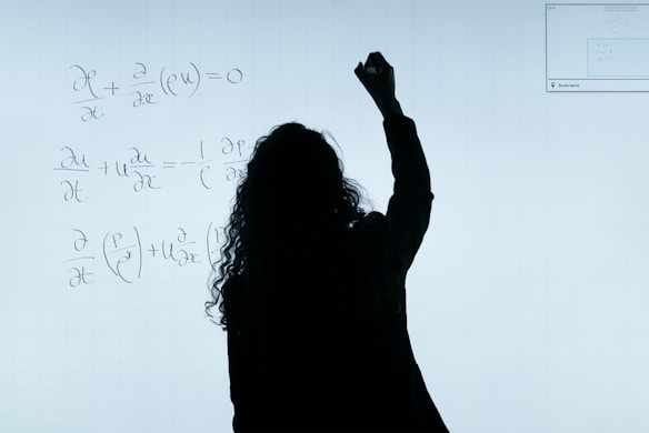 A person stands in front of a whiteboard writing mathematical equations. The silhouette is visible against the softly illuminated board filled with handwritten mathematical expressions.