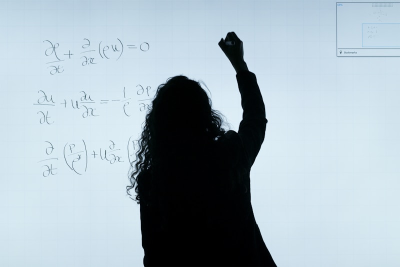 A person stands in front of a whiteboard writing mathematical equations. The silhouette is visible against the softly illuminated board filled with handwritten mathematical expressions.