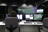 Technician configuring cybersecurity software on multiple monitors in an office setting.