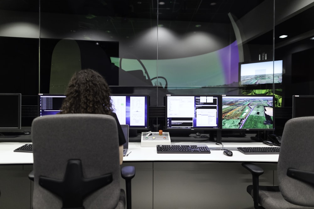 mulher sentada na cadeira preta do rolamento do escritório na frente do monitor do computador