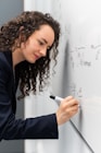 woman in black long sleeve shirt holding pen writing on white paper