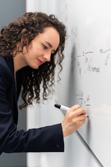 woman in black long sleeve shirt holding pen writing on white paper