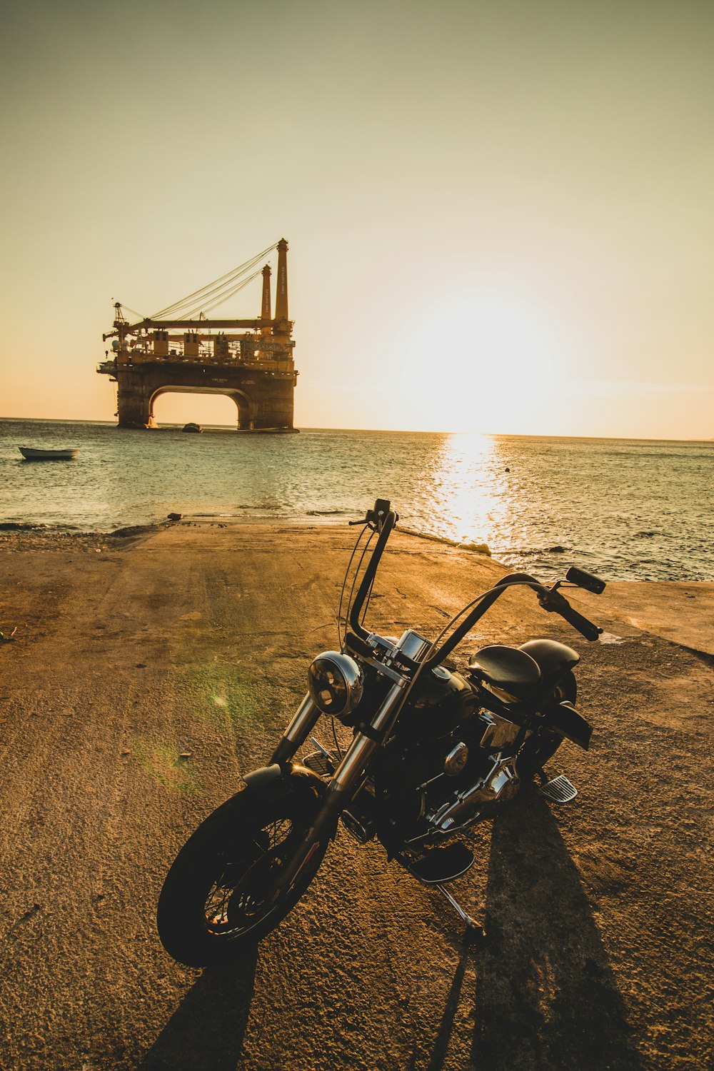 motocicleta negra en la playa durante la puesta del sol