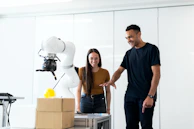 Collaborative robot arm assisting warehouse workers in sorting and packing operations.