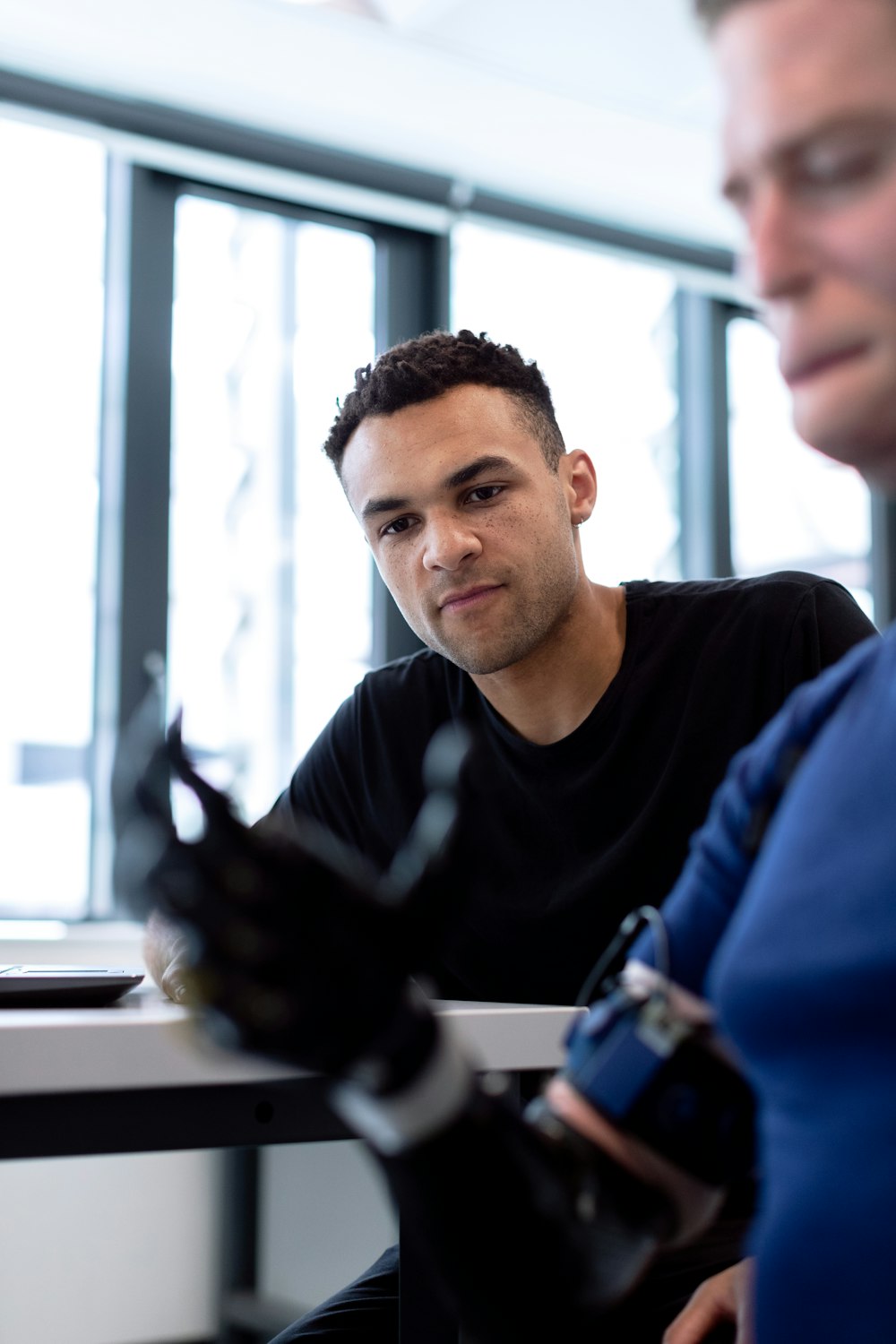 man in black crew neck shirt sitting beside table